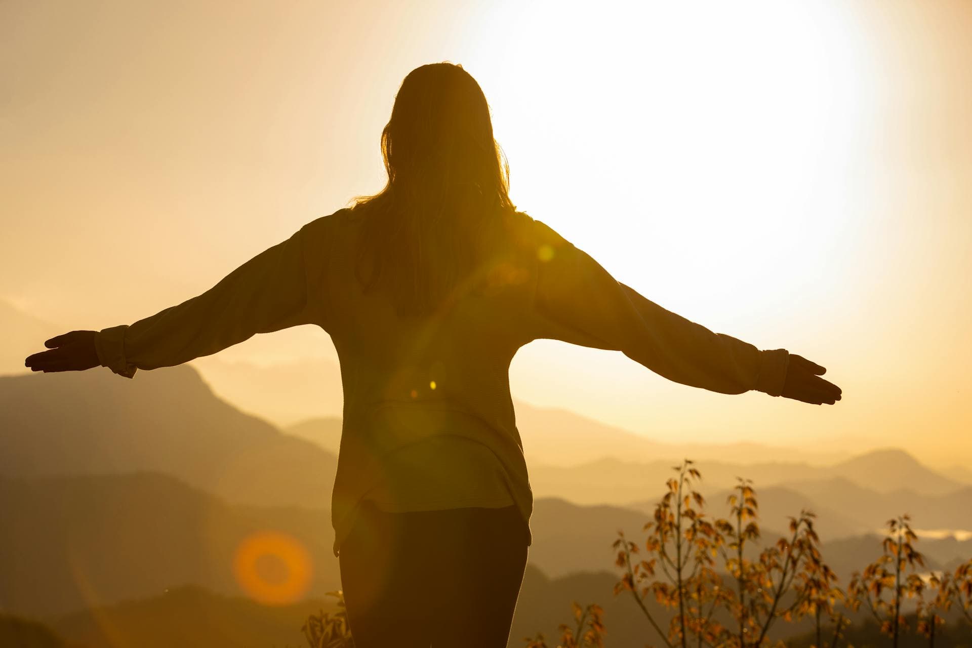 Person extending arms to sun