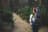 Woman and baby walking down forest path